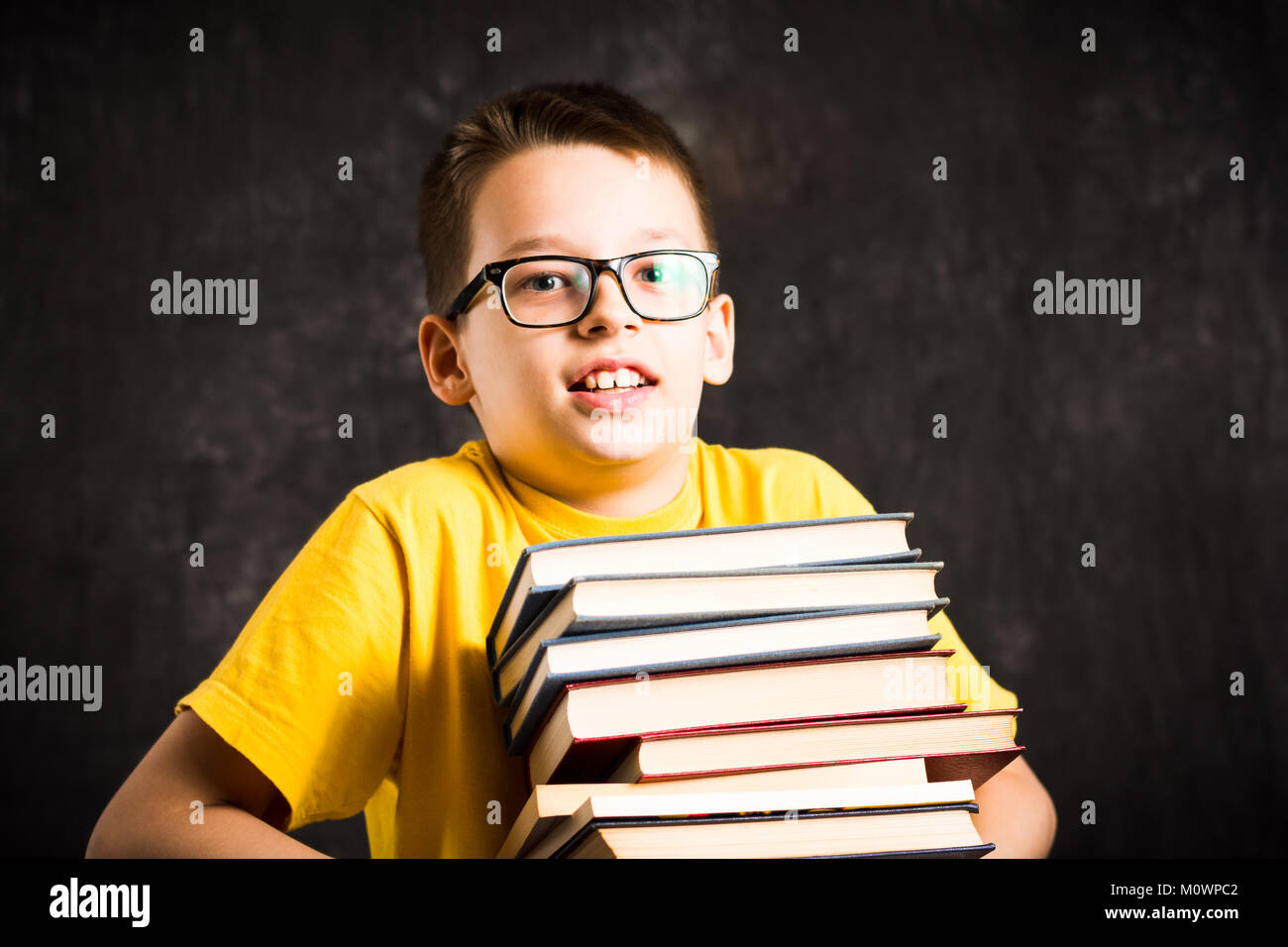 School kid lifting big pile of heavy books Stock Photo