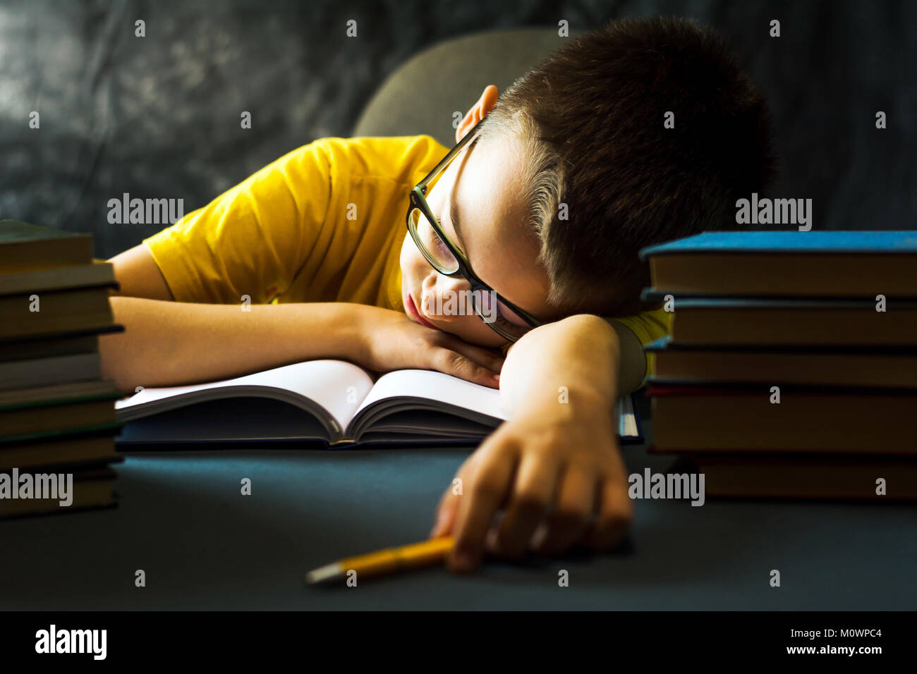 Schoolboy sleeping on the table while finishing homework Stock Photo