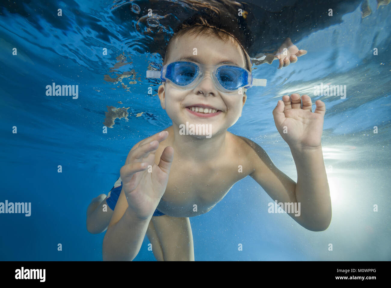 4 years boy in swimming goggles play under water in the pool Stock