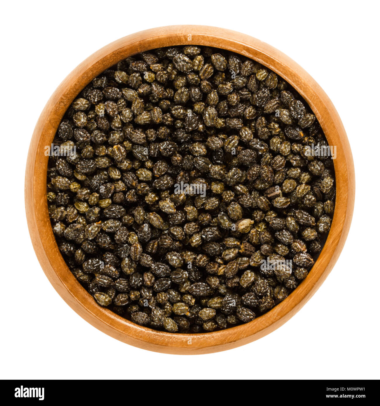 Dried black papaya seeds in wooden bowl. Edible, with sharp, spicy taste, a substitute for pepper and to defeat parasites. Carica papaya. Macro photo. Stock Photo