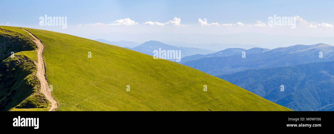 Panorama of green hills in summer mountains with gravel road for ...