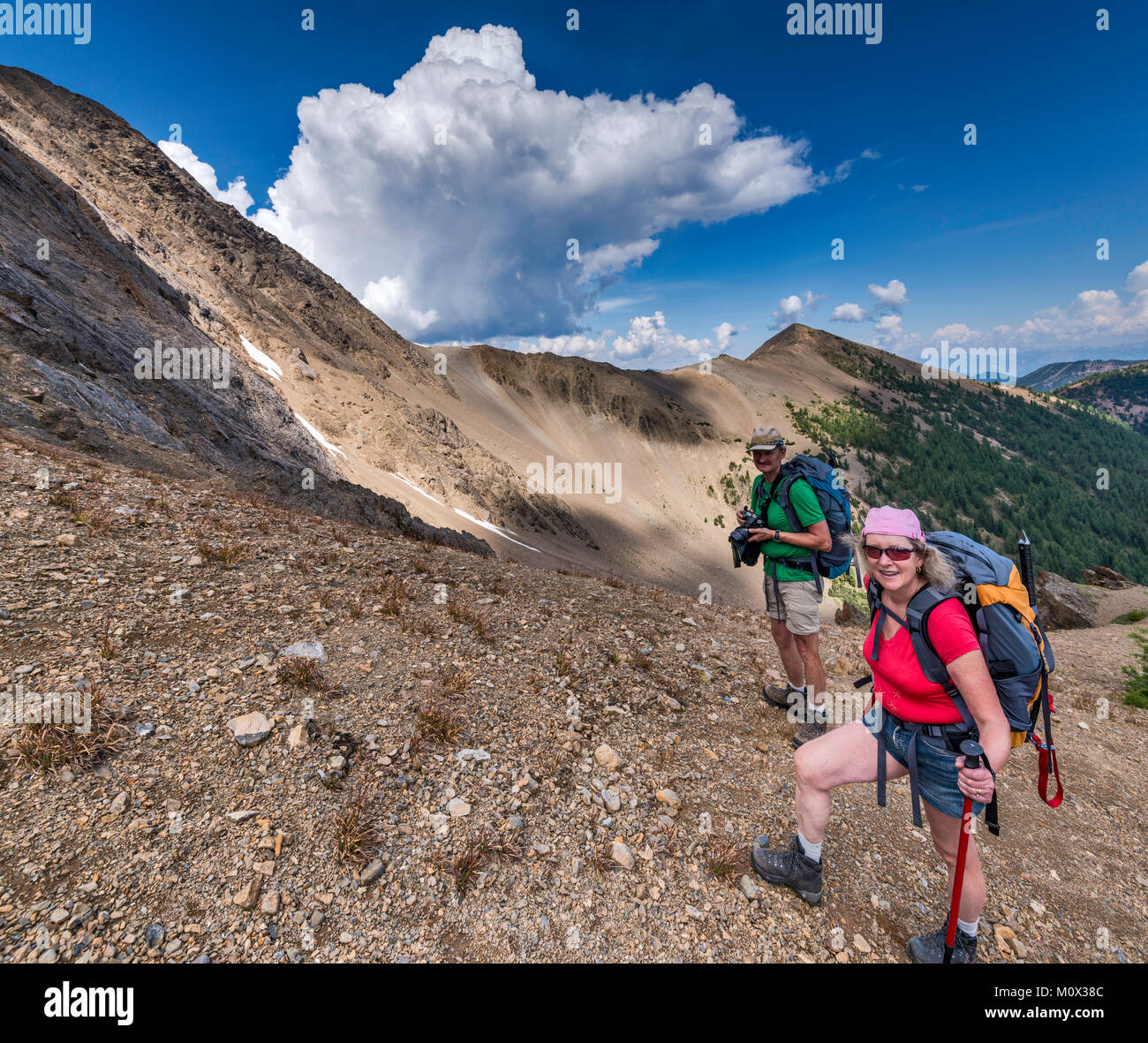 Middle aged hikers ascending scree-covered slopes of Mount Brewer ...