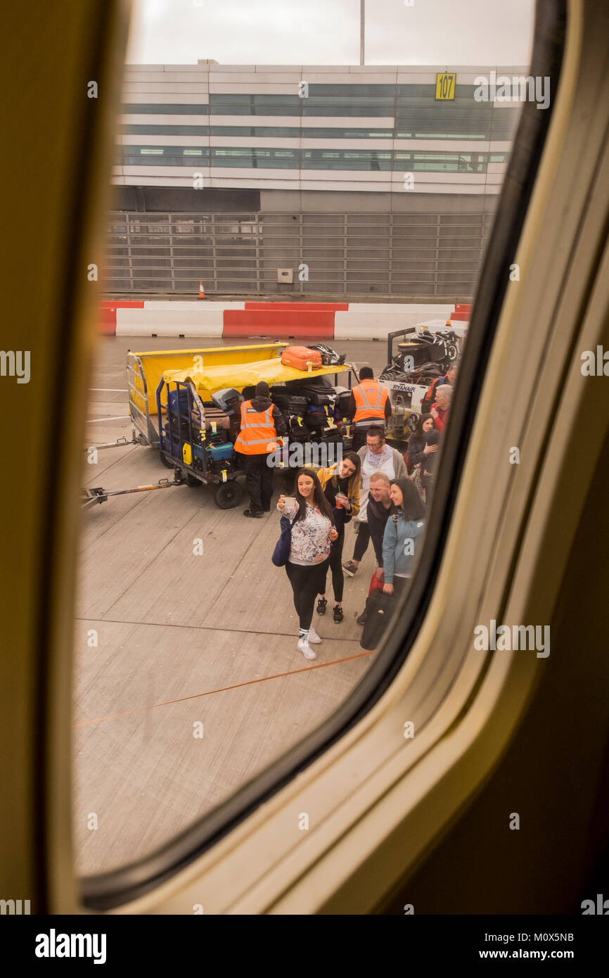 Passengers waiting to board taking a selfie at the bottom of the steps seen through the planes window at Dublin airport, Ireland Stock Photo