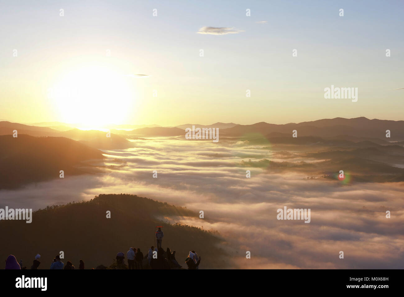 Campers watching the sunrise, while clouds cover the city. Stock Photo