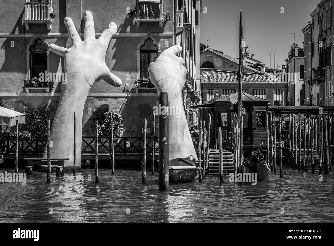 Artwork titled “Support” emerges from Grand Canal, by Lorenzo Quinn, black and white. The contemporary sculpture of giant hands, 2017 Venice Biennale. Stock Photo