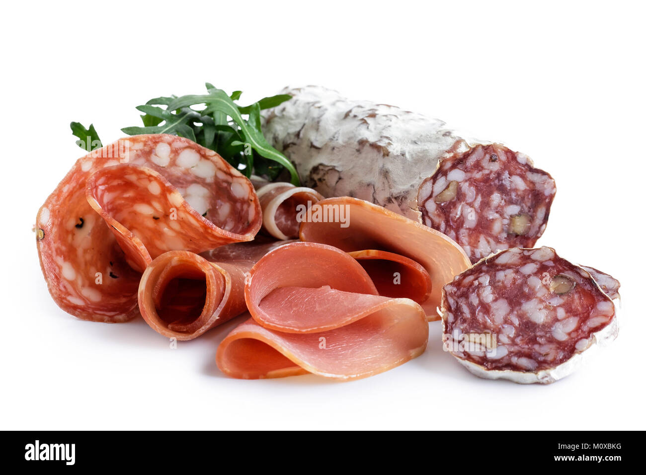 Mixed air cured sliced meats  isolated on white. Rocket garnish. Stock Photo