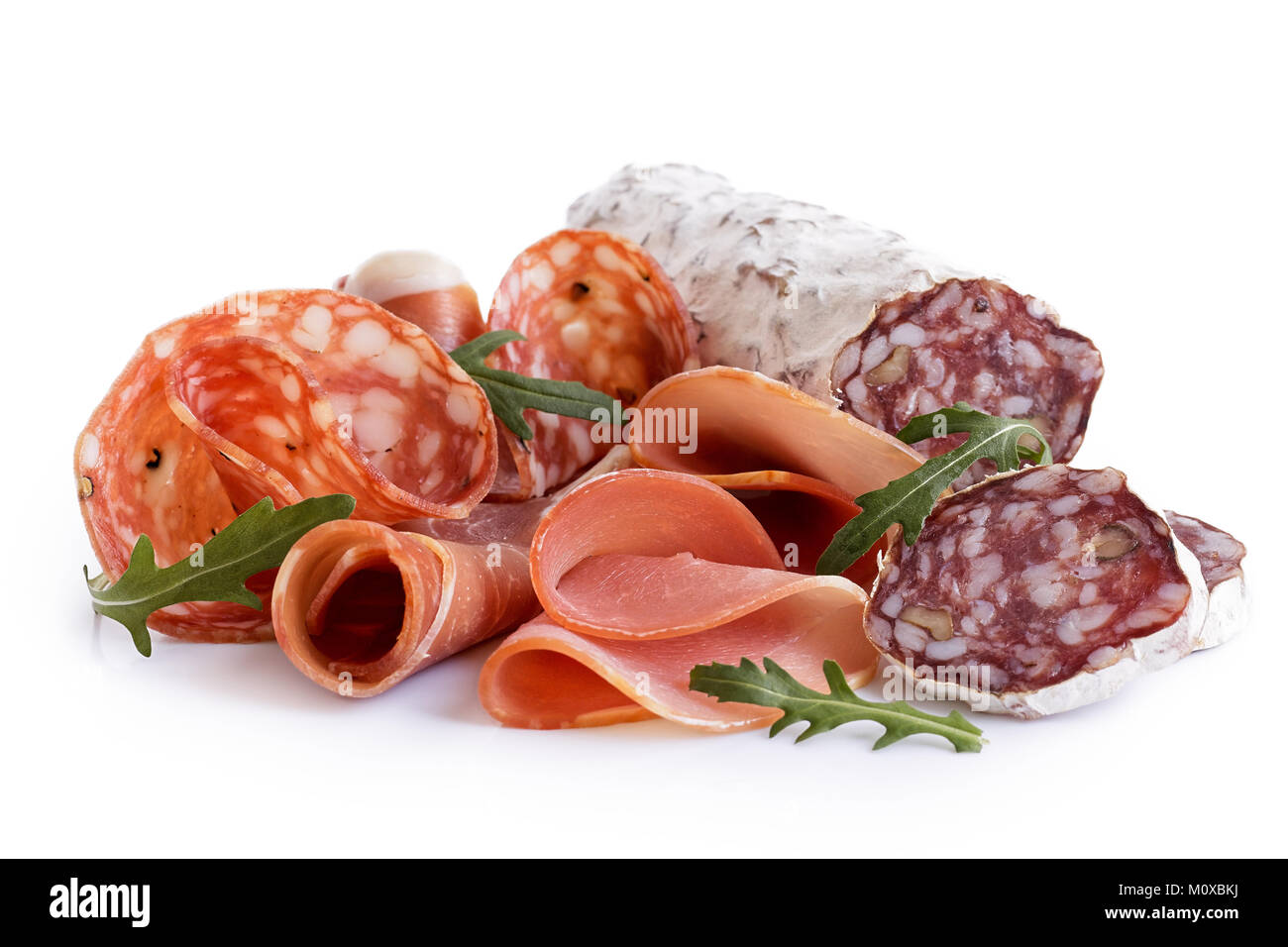Mixed air cured sliced meats isolated on white. Rocket garnish. Stock Photo