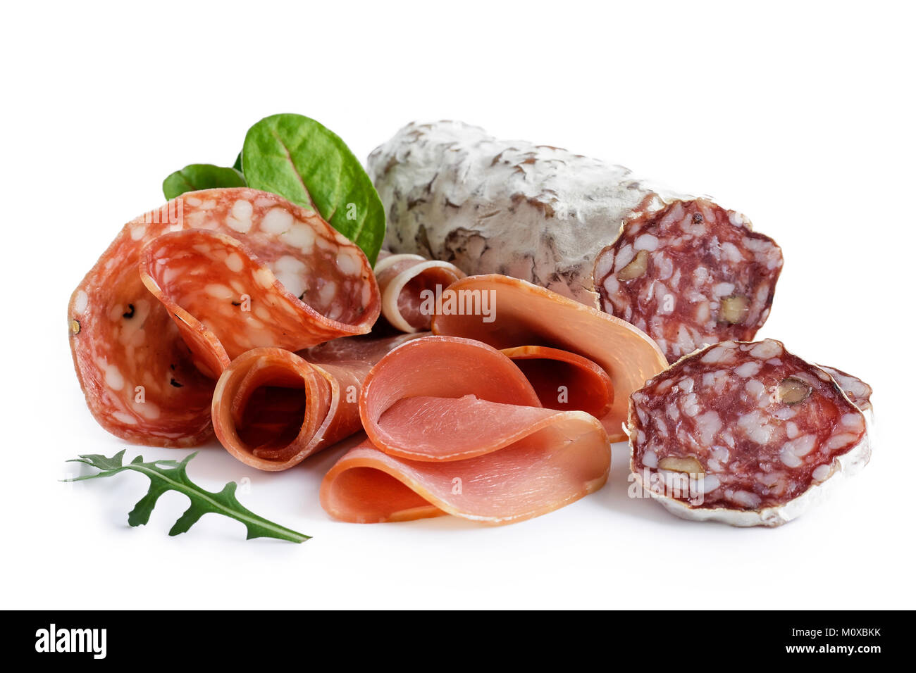 Mixed air cured sliced meats isolated on white. Green leaves. Stock Photo