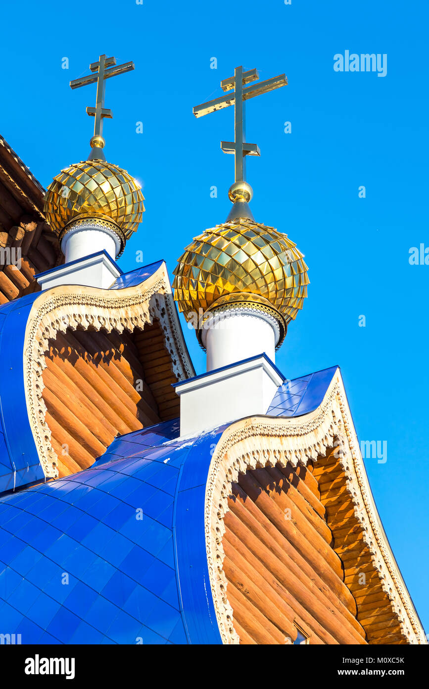 Golden domes with crosses on wooden orthodox church against the blue ...