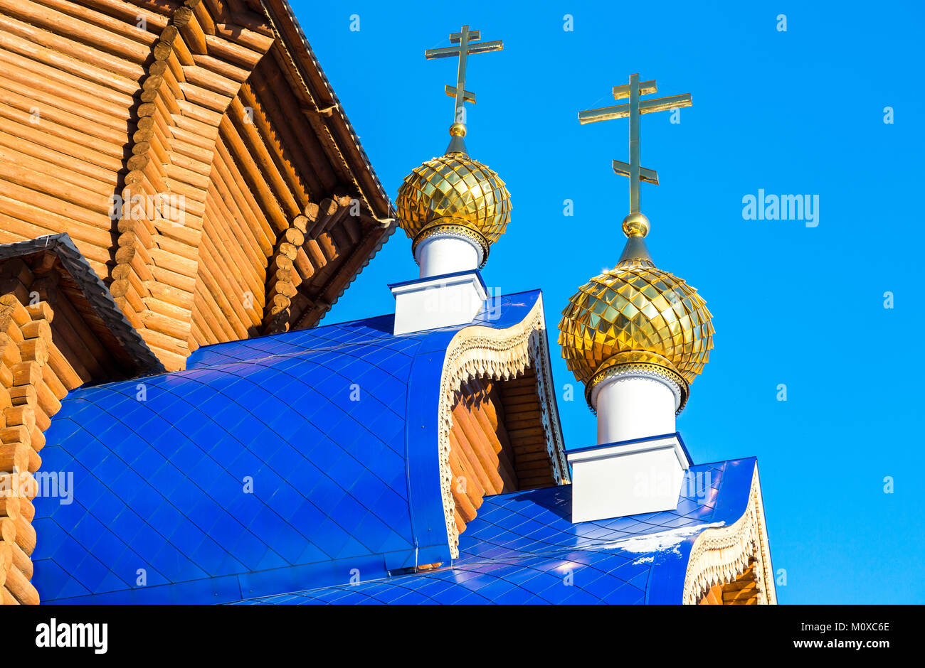 Golden domes with crosses on wooden orthodox church against the blue ...