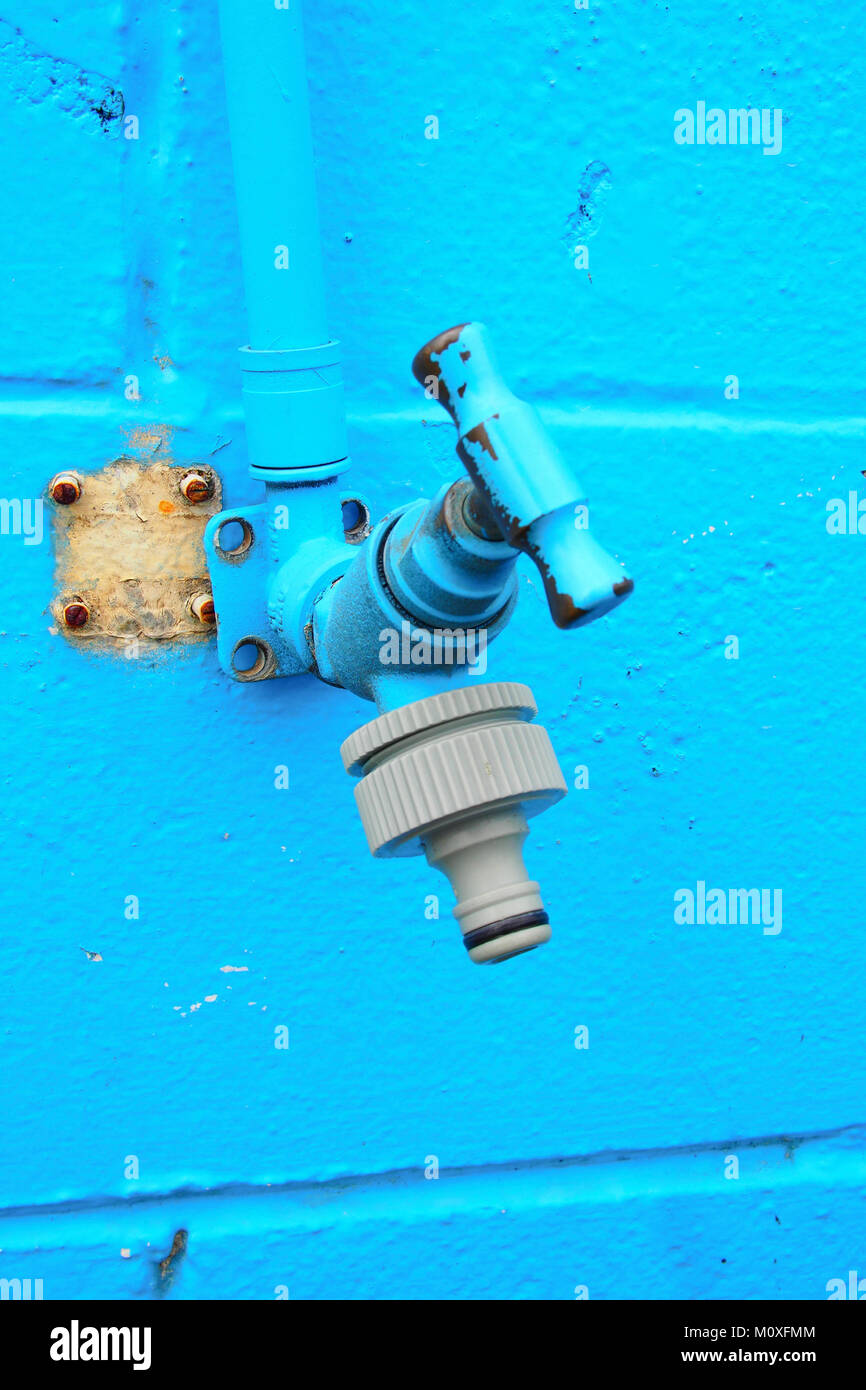 blue faucet on blue concrete wall Stock Photo