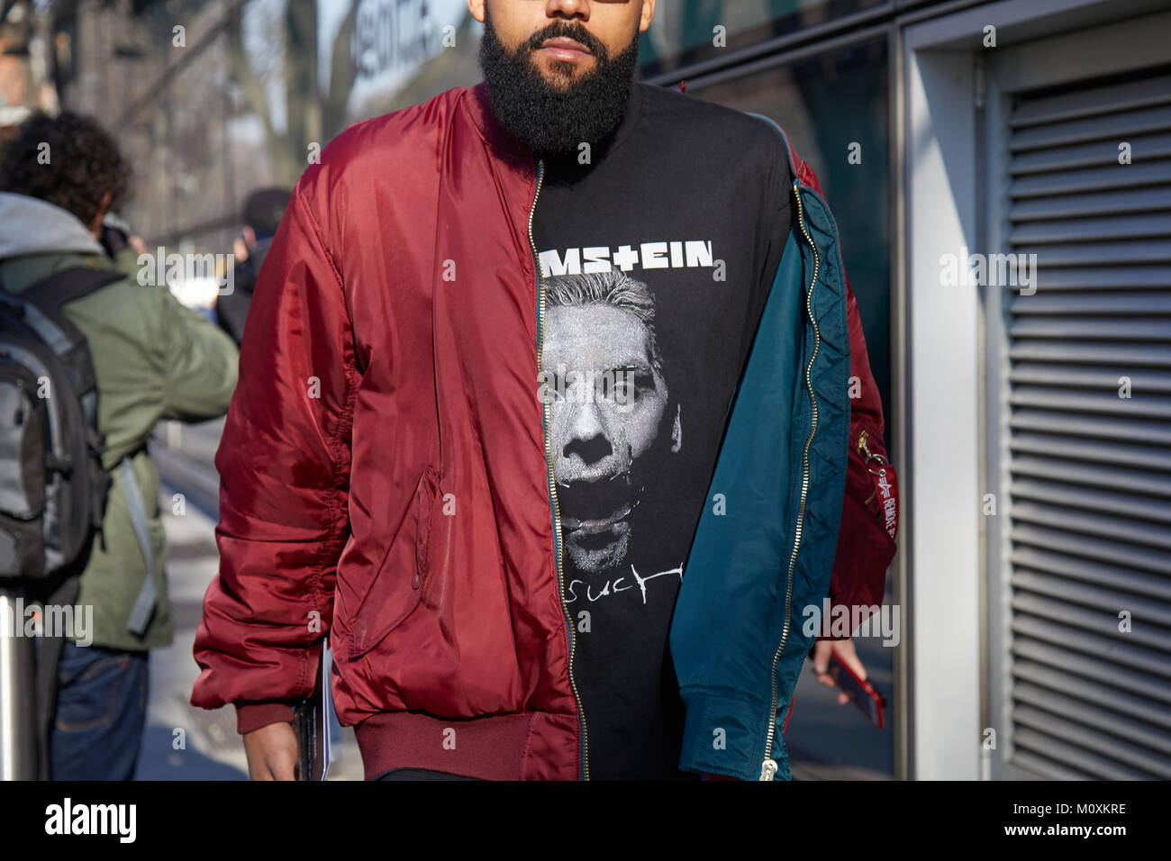 MILAN - JANUARY 13: Man with dark red bomber jacket and Rammstein shirt before Emporio Armani fashion show, Milan Fashion Week street style on January Stock Photo