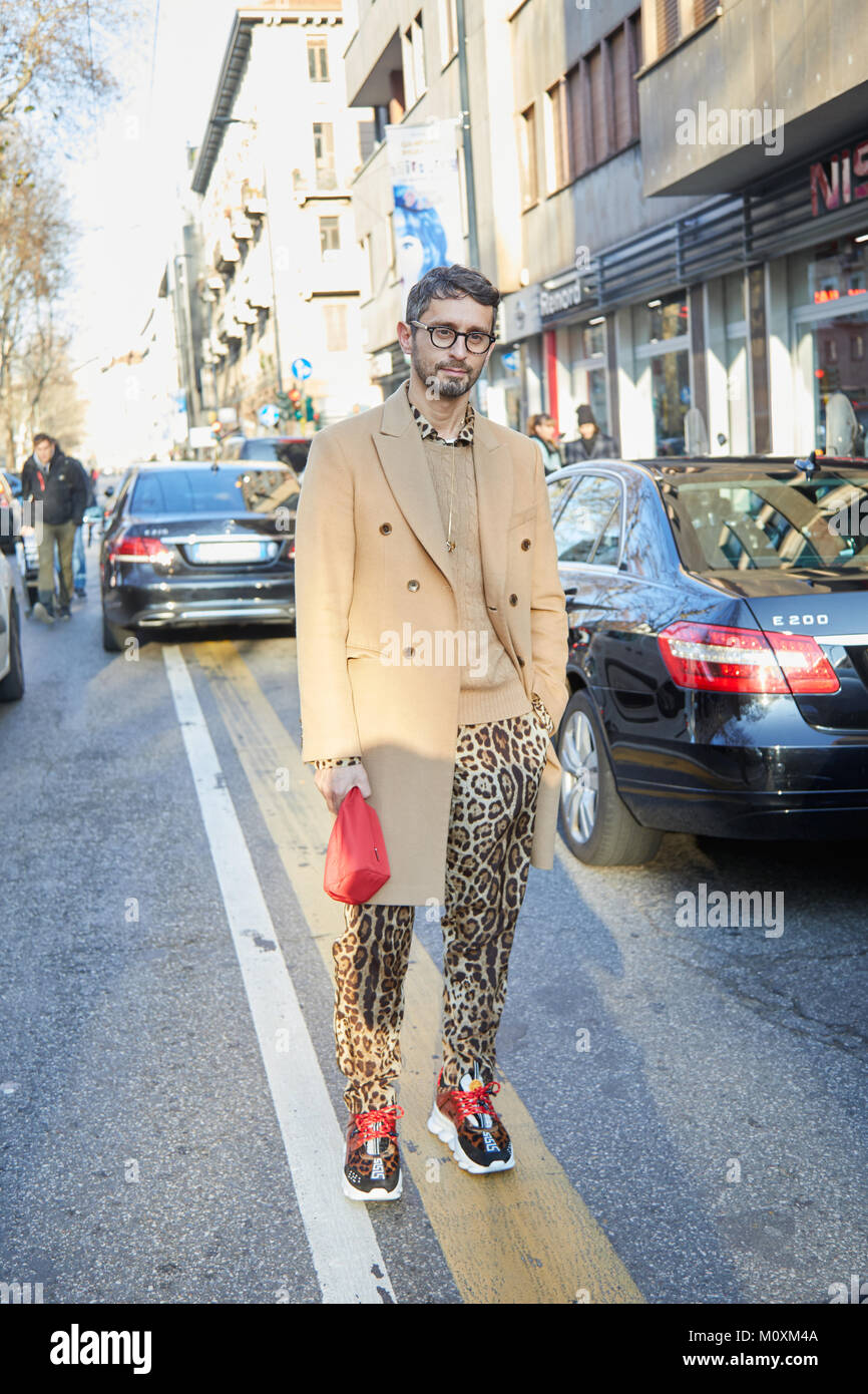 MILAN - JANUARY 13: Man with beige coat and leopard skin print trousers before Marni fashion show, Milan Fashion Week street style on January 13, 2018 Stock Photo