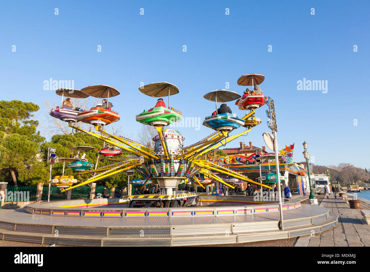 Adults and children riding on an elevated carousel on Riva dei Sette ...