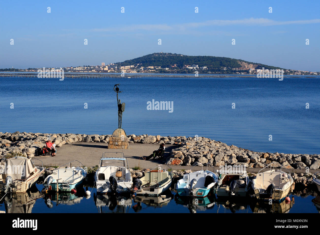 The fishing port of Meze, boats, sculpture in the background the Mont St Clair of Sete, Pond of Thau, Occitanie France Stock Photo