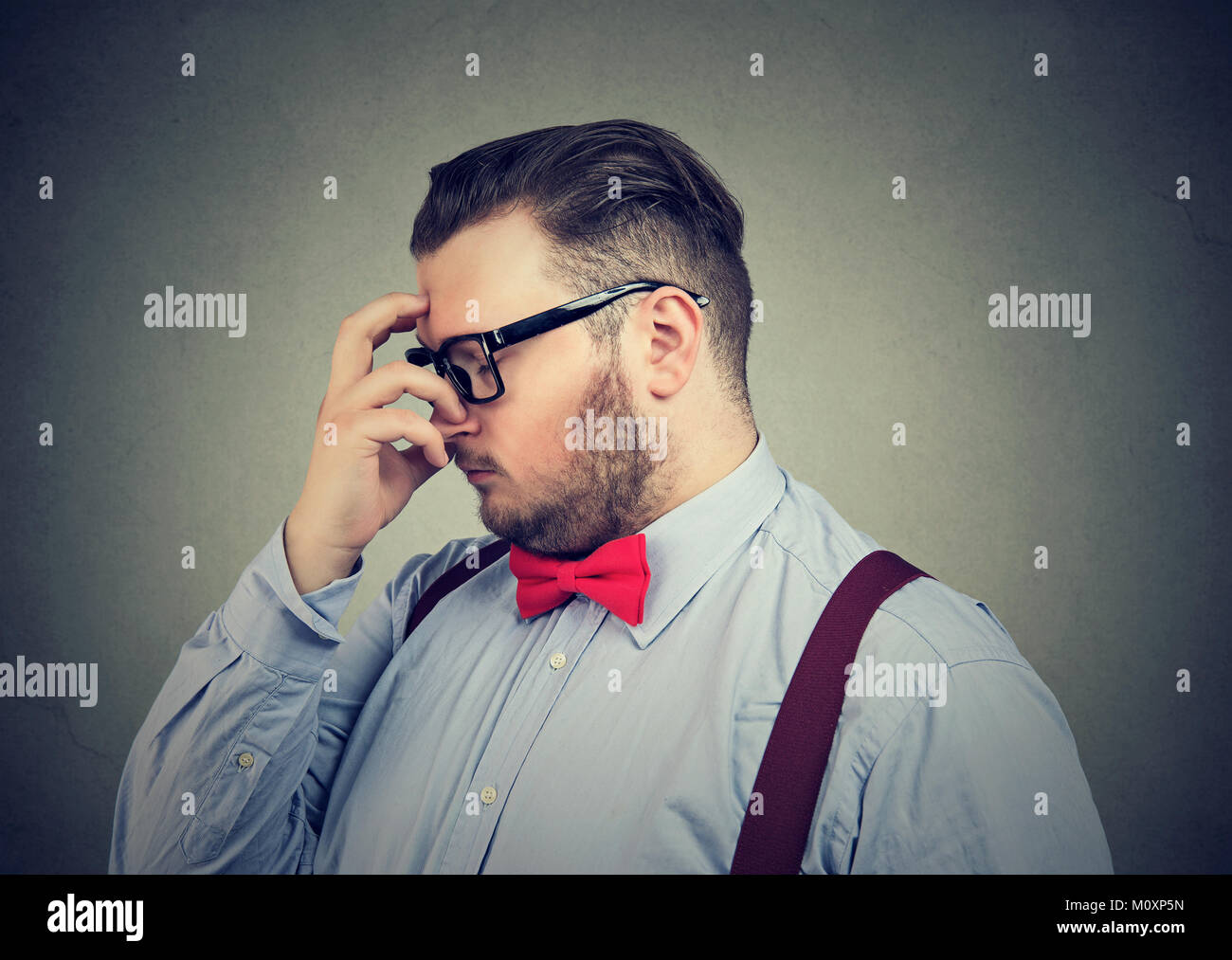 Young man rubbing forehead trying to solve difficult problem. Stock Photo