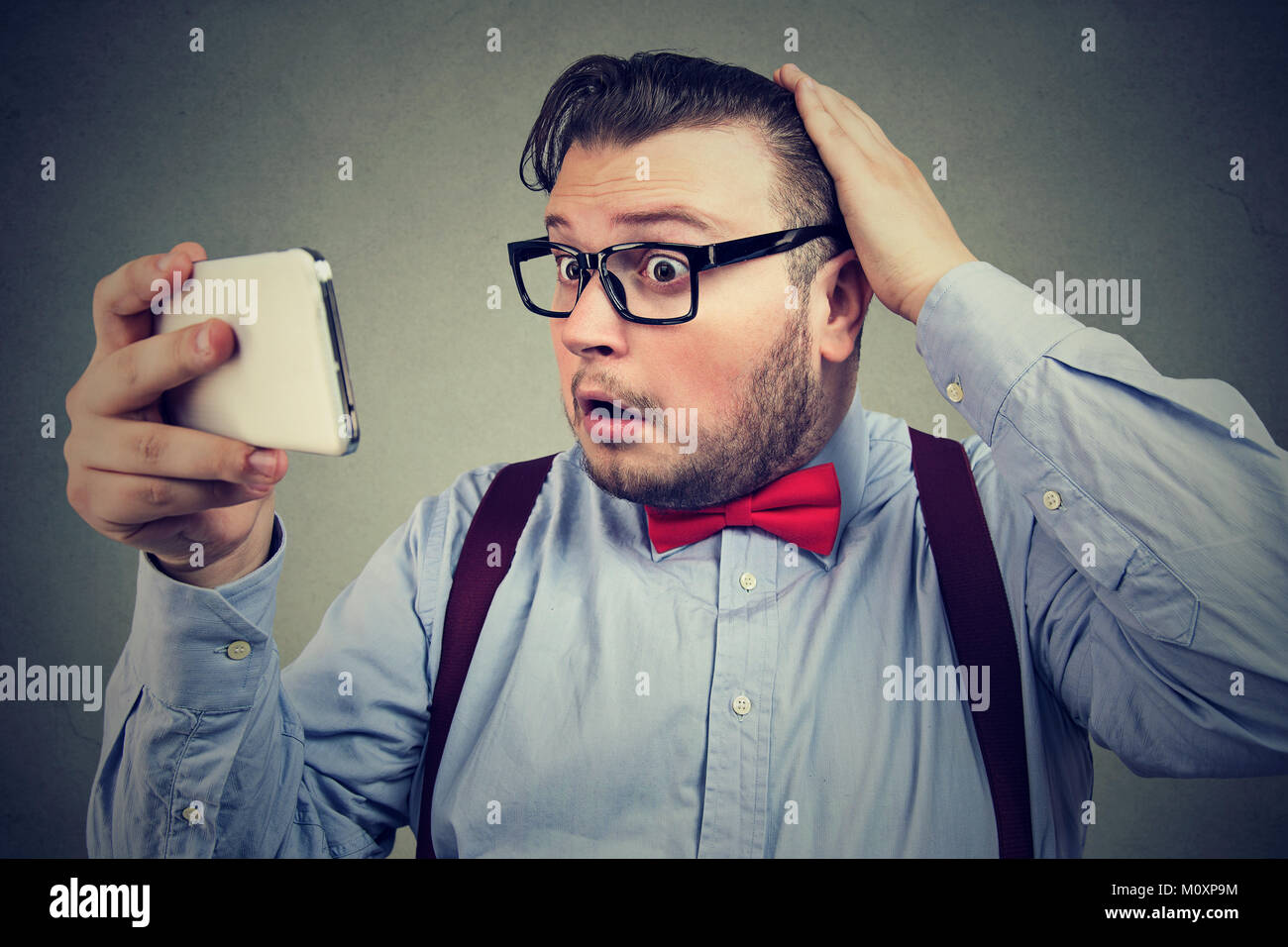 Chunky young man exploring reflection and looking surprised when losing hair. Stock Photo