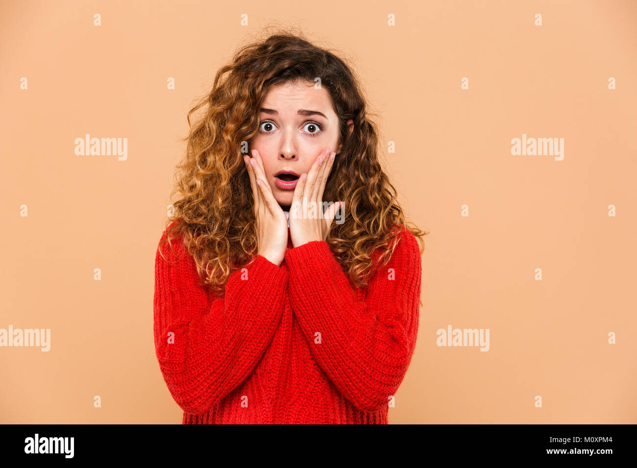 Close up portrait of a shocked pretty girl holding hands at her face ...