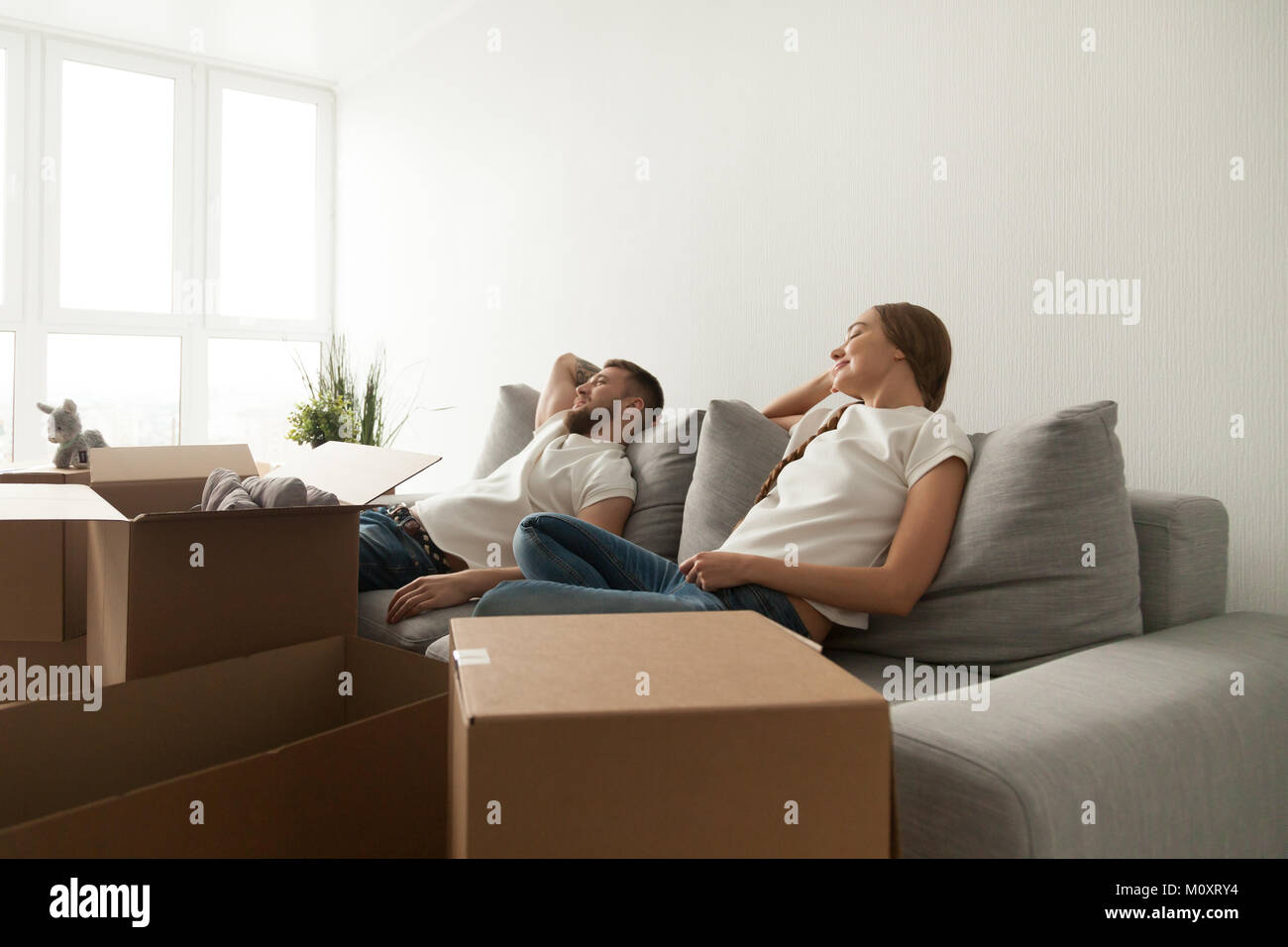 Young couple relaxing on couch just moved into new home Stock Photo