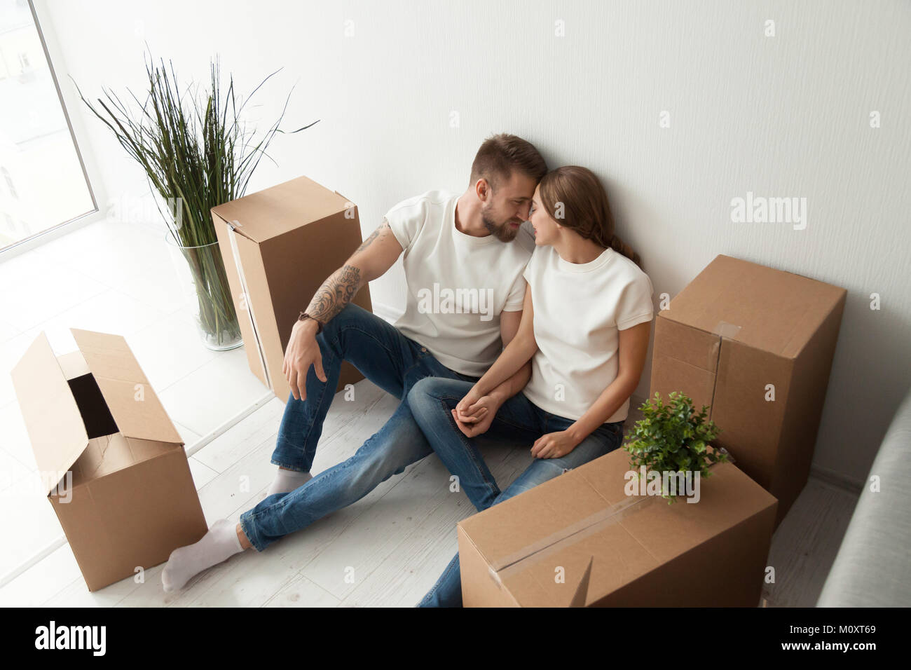 Young couple bonding sitting on the floor with moving boxes Stock Photo