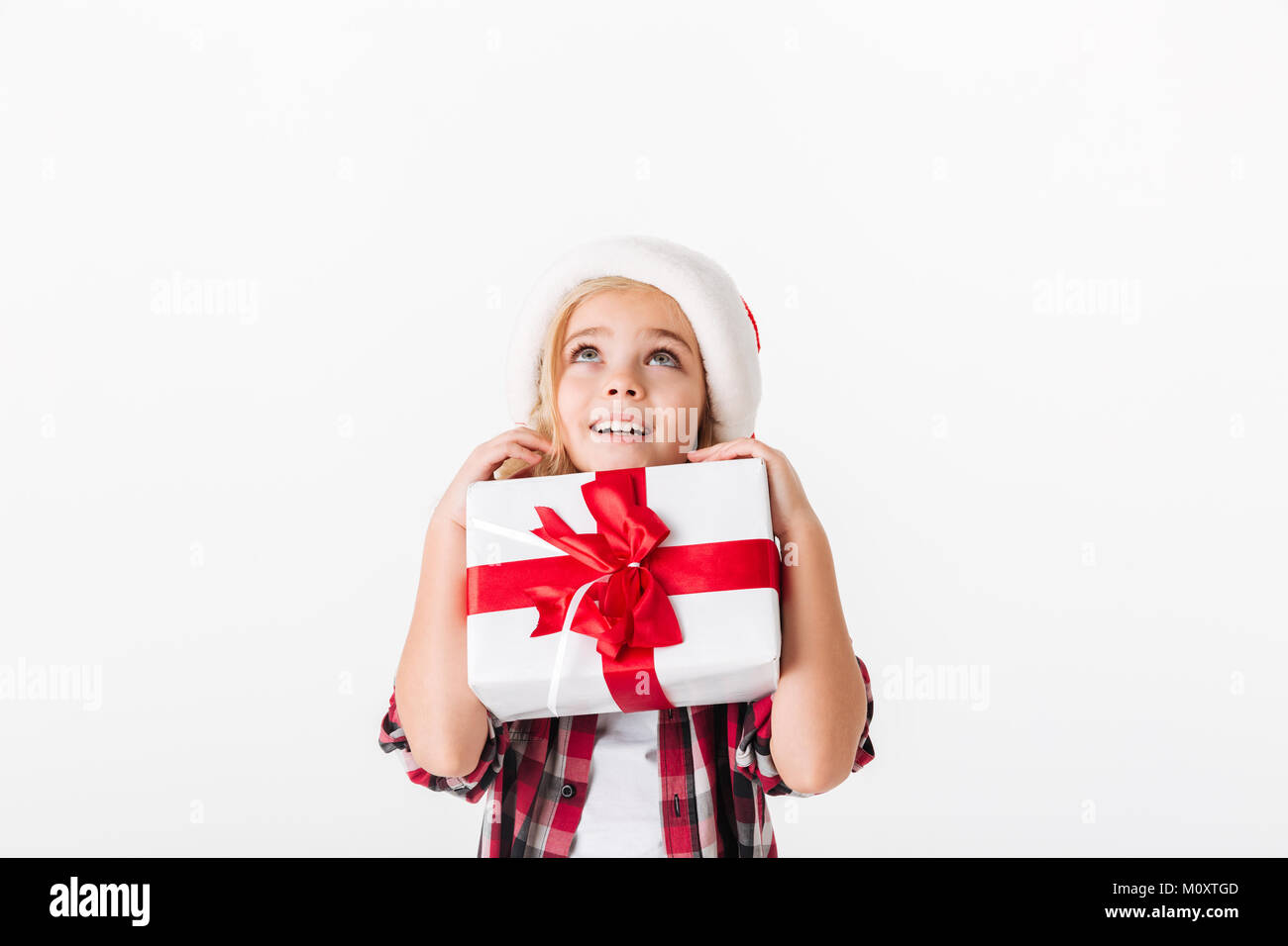 Portrait of a smiling little girl holding gift box and looking up at ...