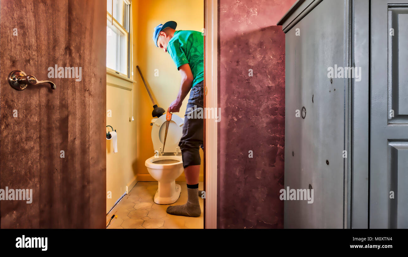 A bachelor man unclogging the toilet. Stock Photo