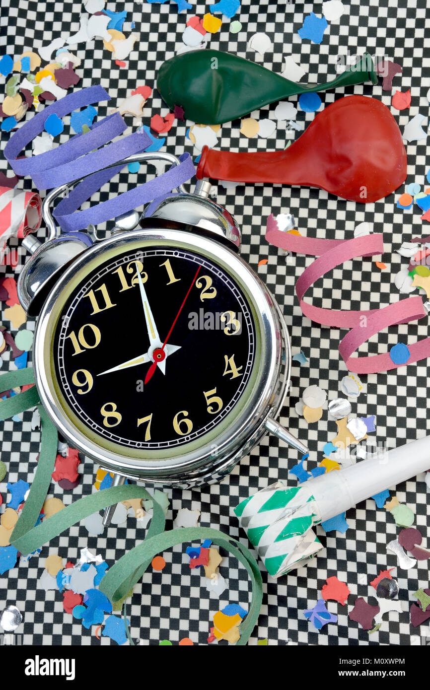 Party time concept with an alarm clock, streamers and noisemaker on