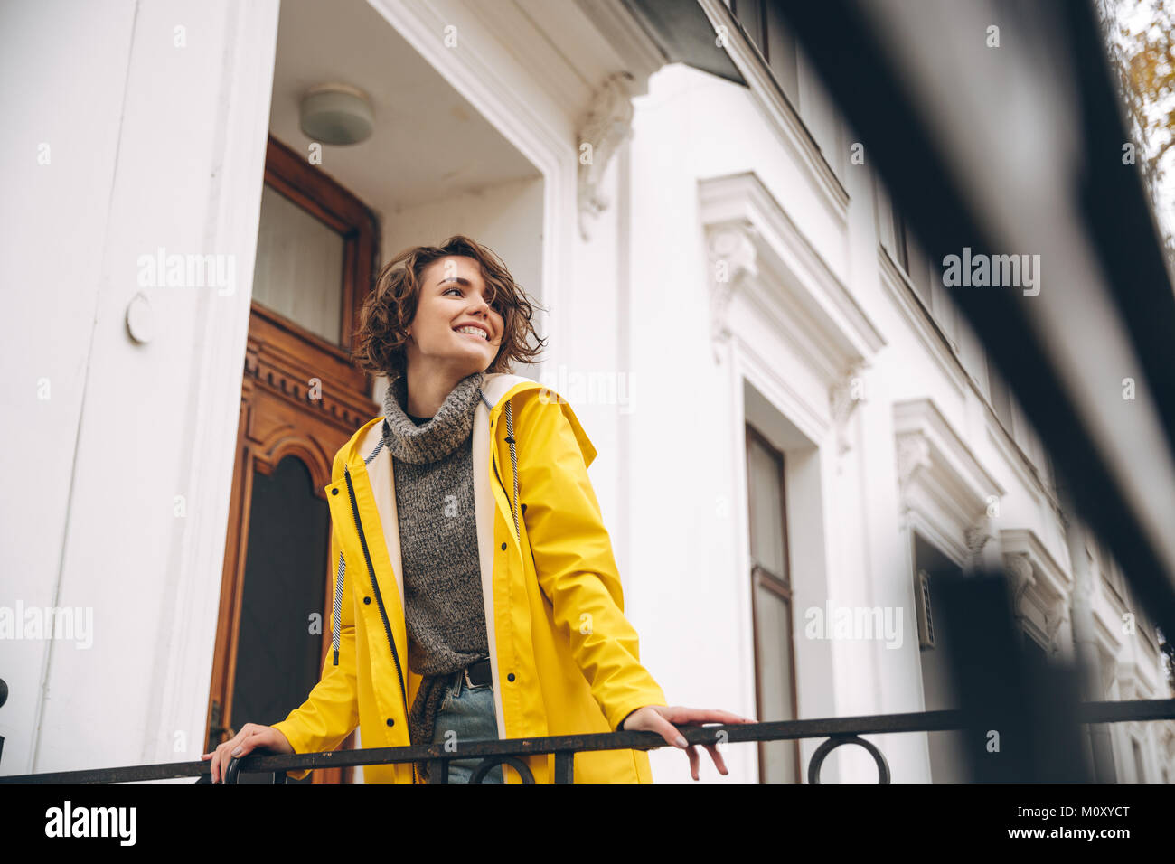 Image of happy pretty young woman dressed in yellow raincoat walking ...