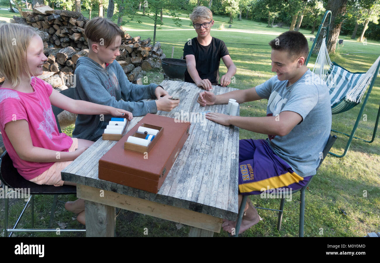 Children totally engrossed in playing poker with chips outside at the lake cabin. Clitherall Minnesota MN USA Stock Photo