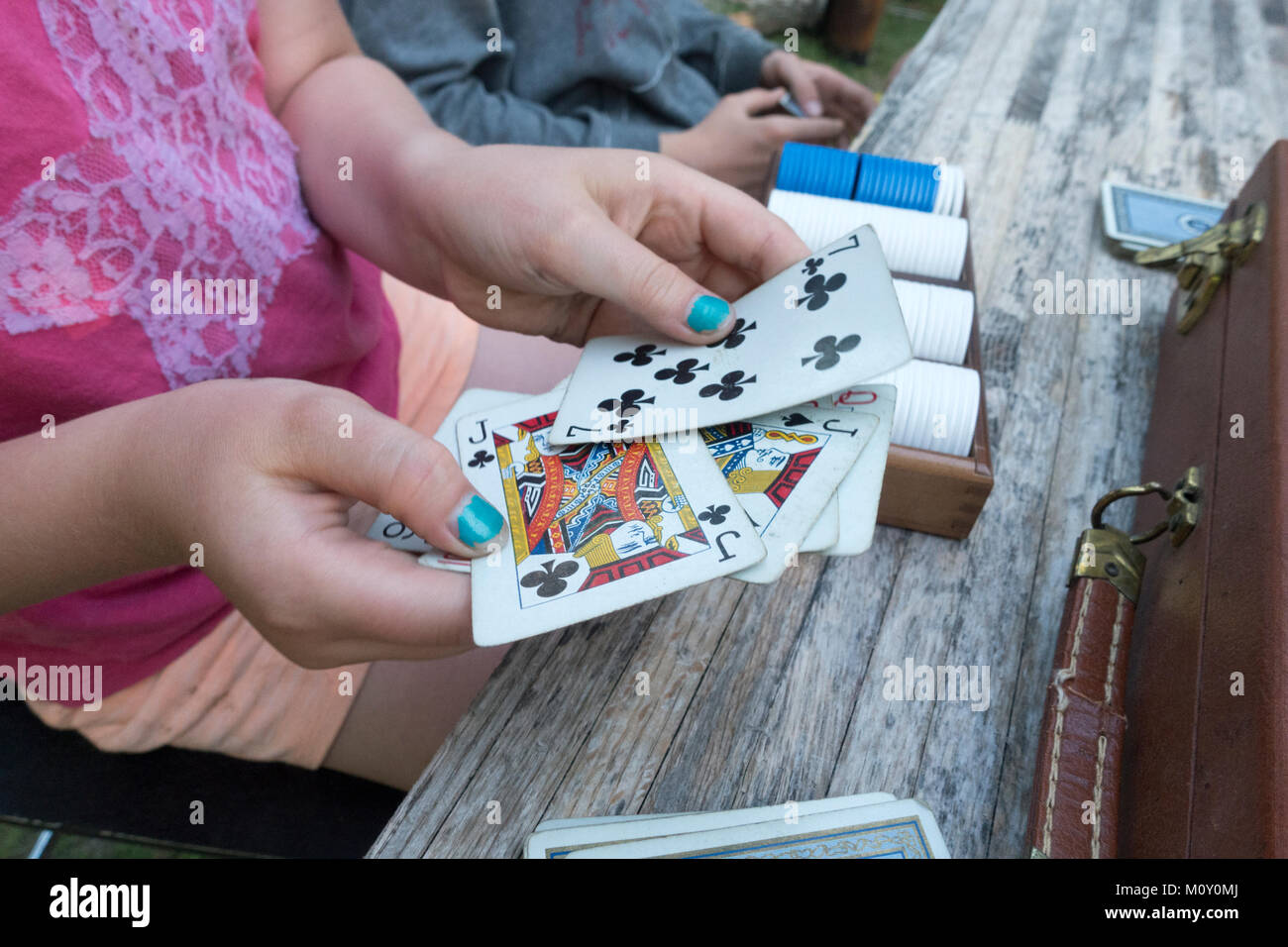 Looks like a pair of Jacks in a poker hand of a young girl with turquoise painted nails. Clitherall Minnesota MN USA Stock Photo