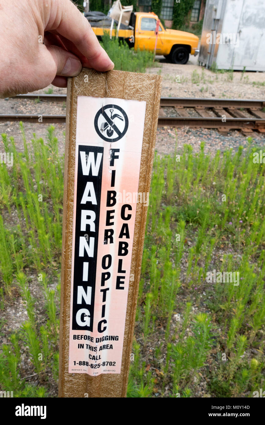 Warning sign that fiber optic cable has been buried along this thoroughfare near the railroad tracks. Minneapolis Minnesota MN USA Stock Photo