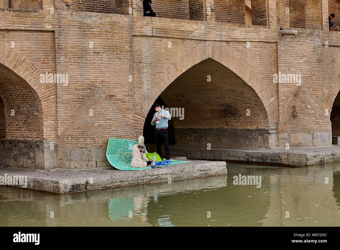 Isfahan, Iran - April 24, 2017: The Iranian couple took a picnic at the foot of the Allahverdi Khan bridge. Stock Photo