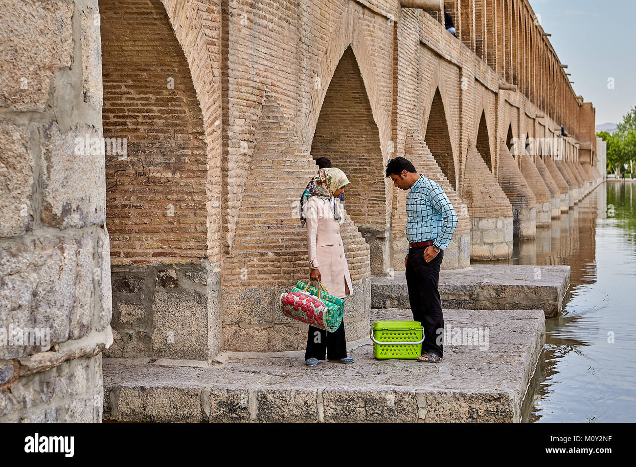 Isfahan, Iran - April 24, 2017: A man and a girl came to the bridge of Allahverdi Khan to have a picnic near the river Zayandeh. Stock Photo