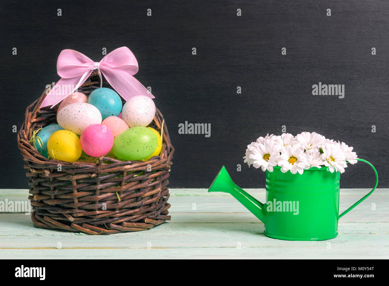 Wicker basket full of painted Easter eggs and a pink ribbon bow and a ...