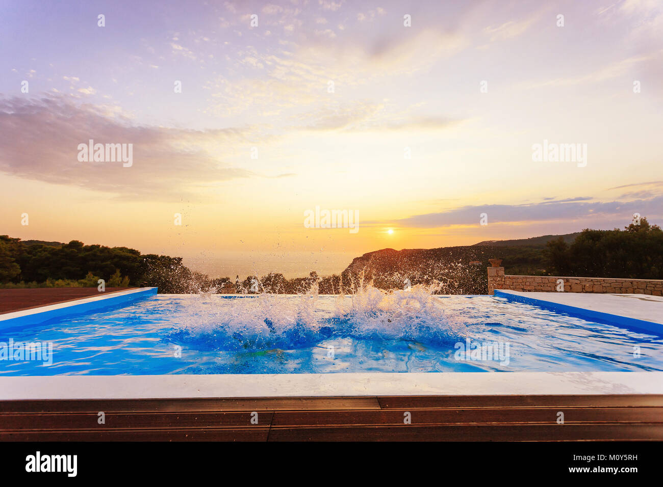 kids jump in the pool with sunset and beautiful view of a summer resort Stock Photo