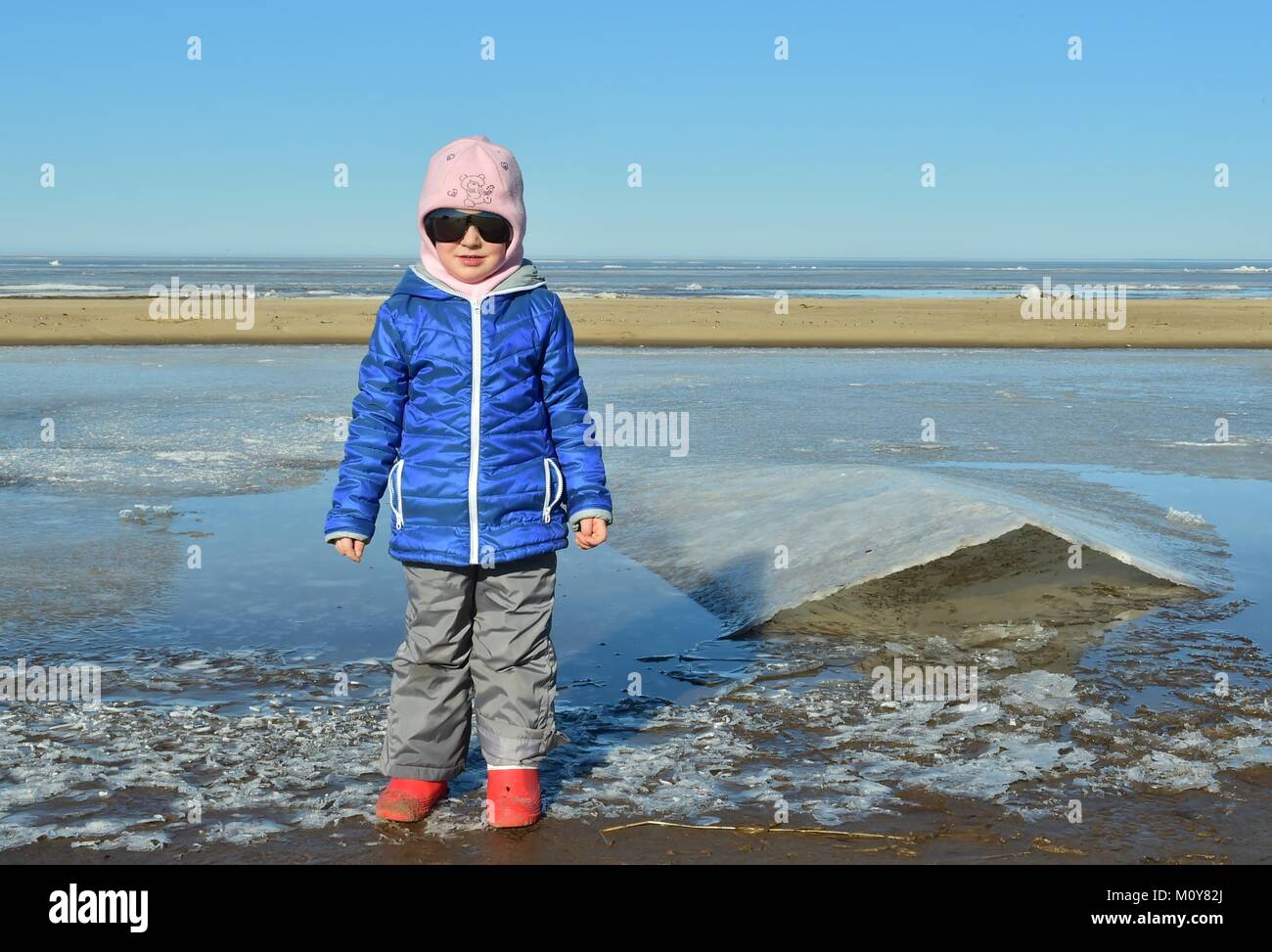 The little girl in big sunglasses on ice. Winter Stock Photo