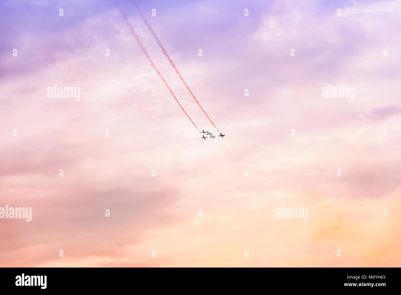 Group of aircraft flying at sunset. Exciting performance. Air performance, air show, aircrafts, flying display and skill teamwork. Abstract background Stock Photo