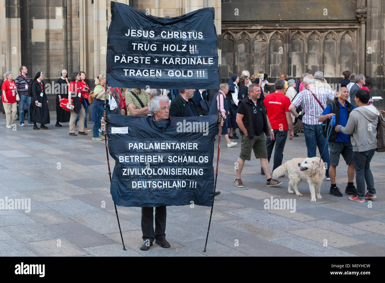 Germany, Cologne, demonstrator in front of the cathedral (translation: jesus wears wood. popes and cardinals wears gold and parliamentarians shameless Stock Photo