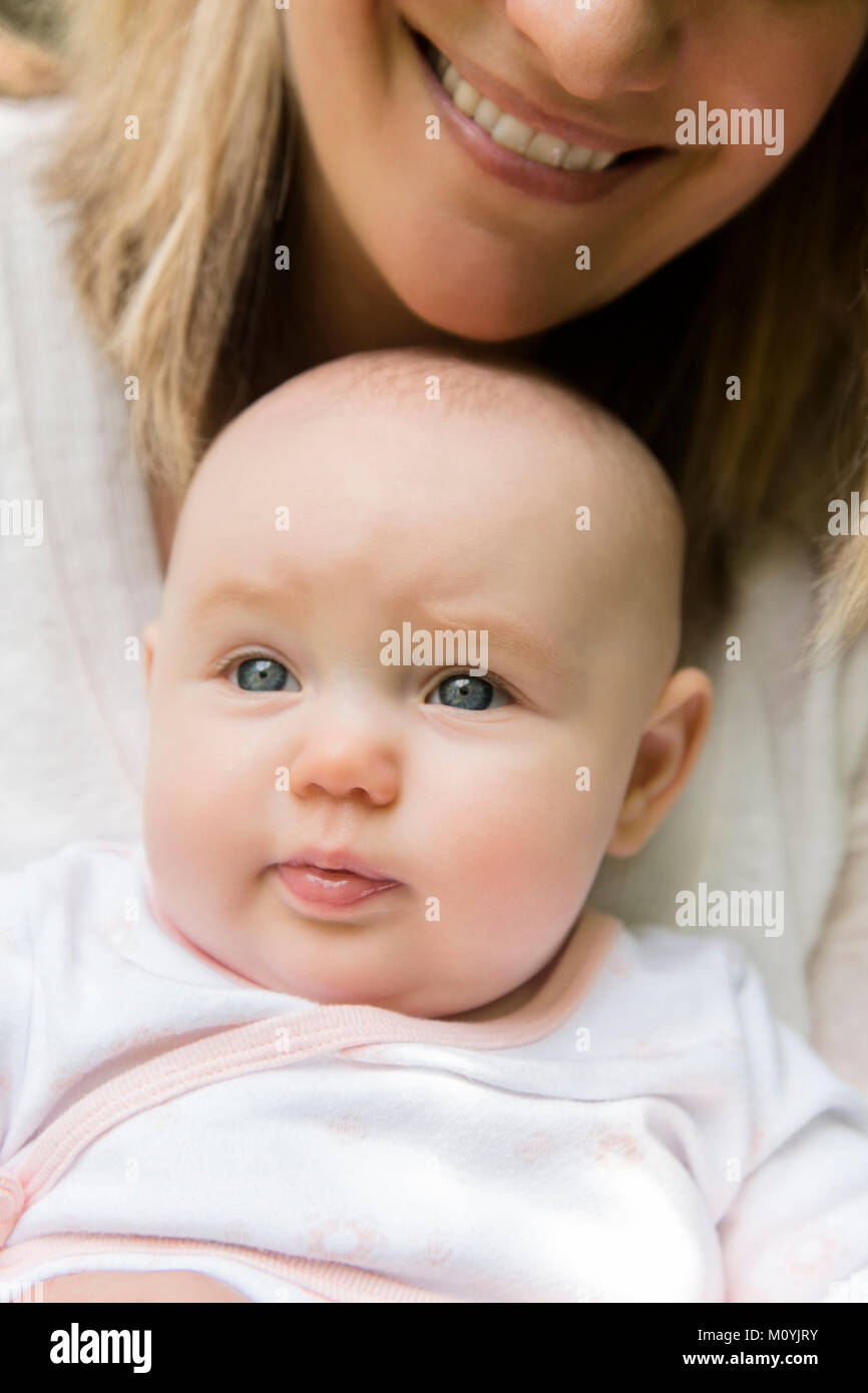 Smiling Caucasian mother holding baby daughter in lap Stock Photo