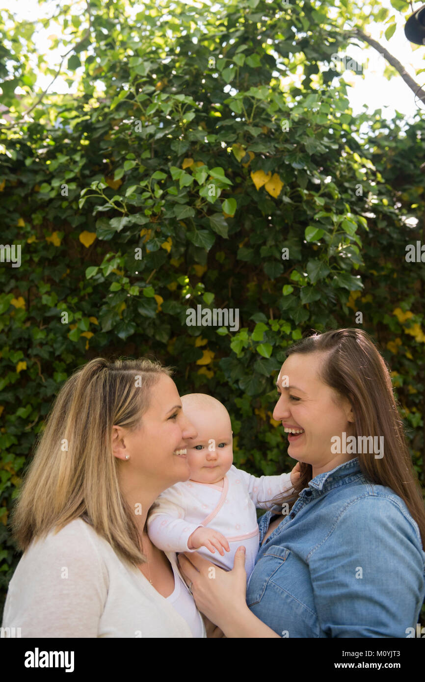 Caucasian mothers hugging baby daughter near tree Stock Photo