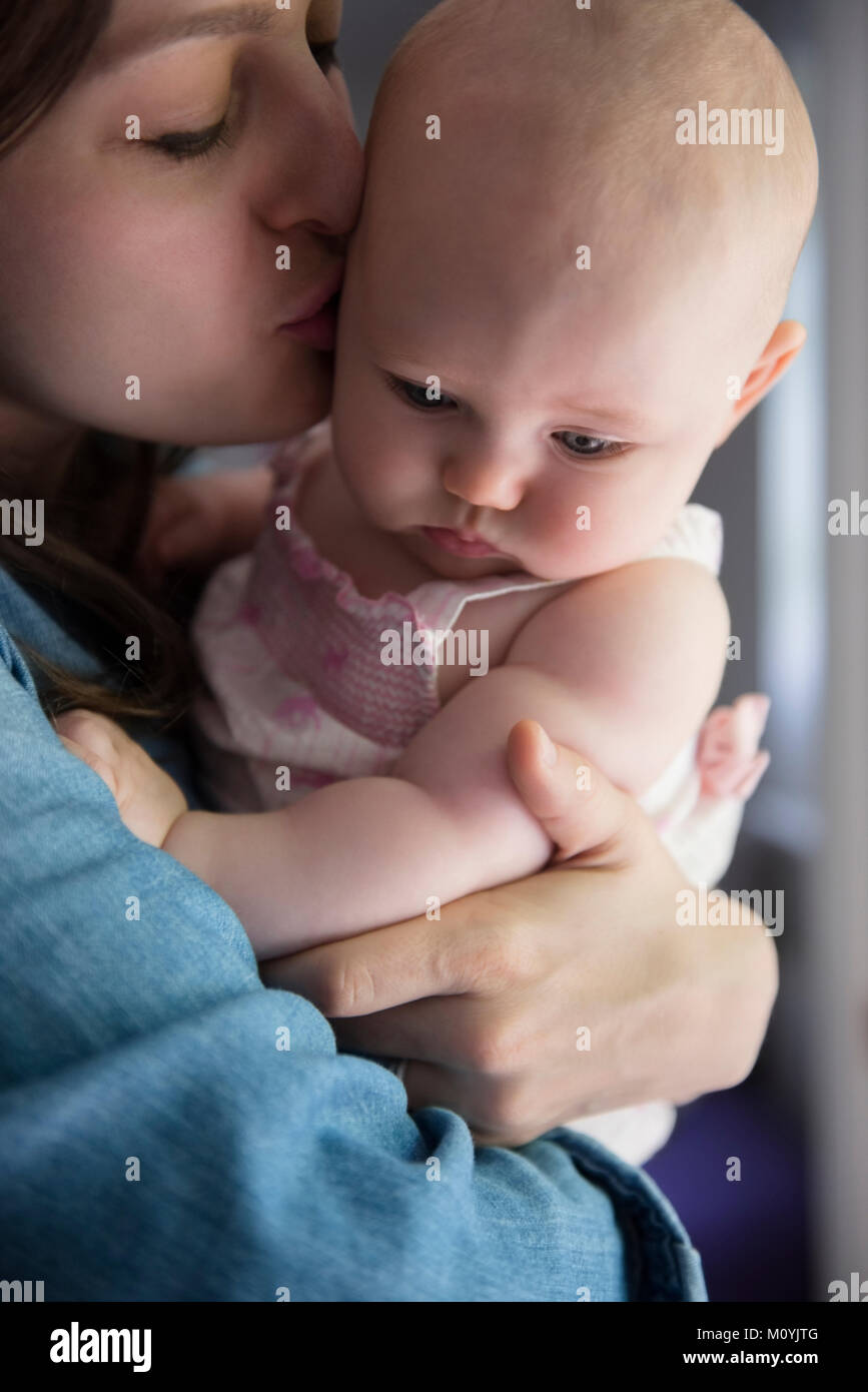 Caucasian mother kissing cheek of baby daughter Stock Photo