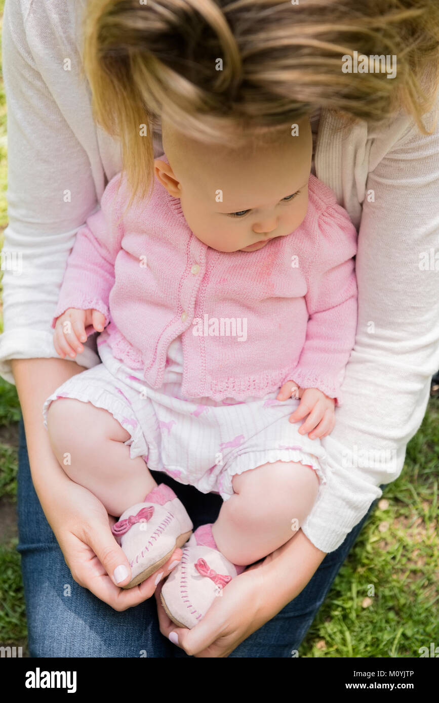Close up of Caucasian baby girl sitting in lap of mother Stock Photo