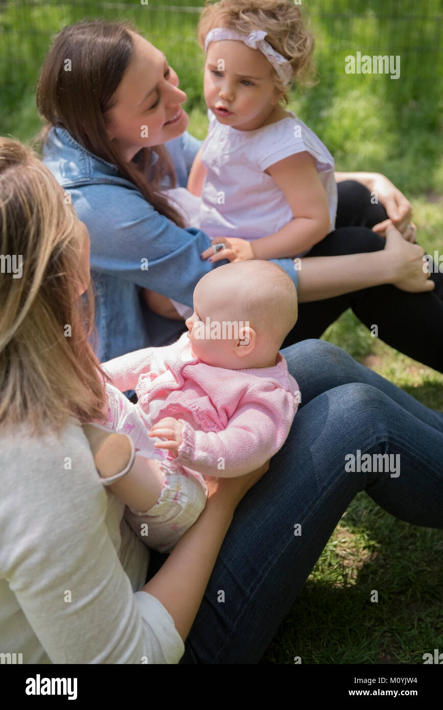 Caucasian mothers and daughters sitting in grass Stock Photo