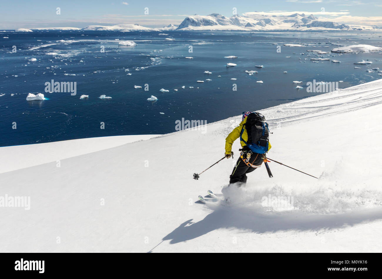 Female professional alpine ski mountaineer guide skiing downhill in