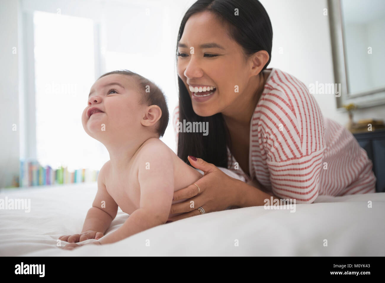 Mother playing with baby son laying on bed Stock Photo