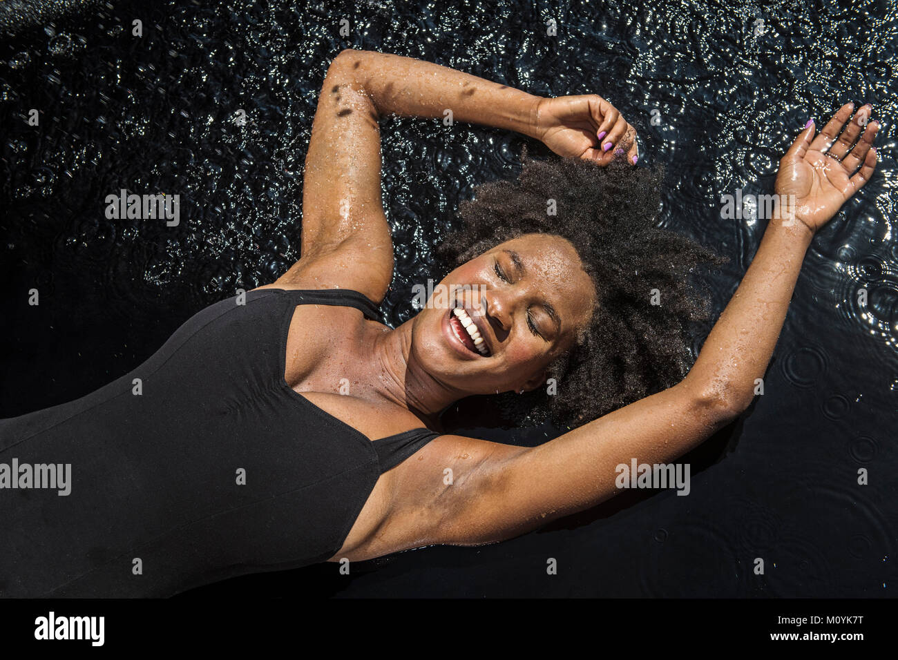 Laughing black woman laying in water Stock Photo