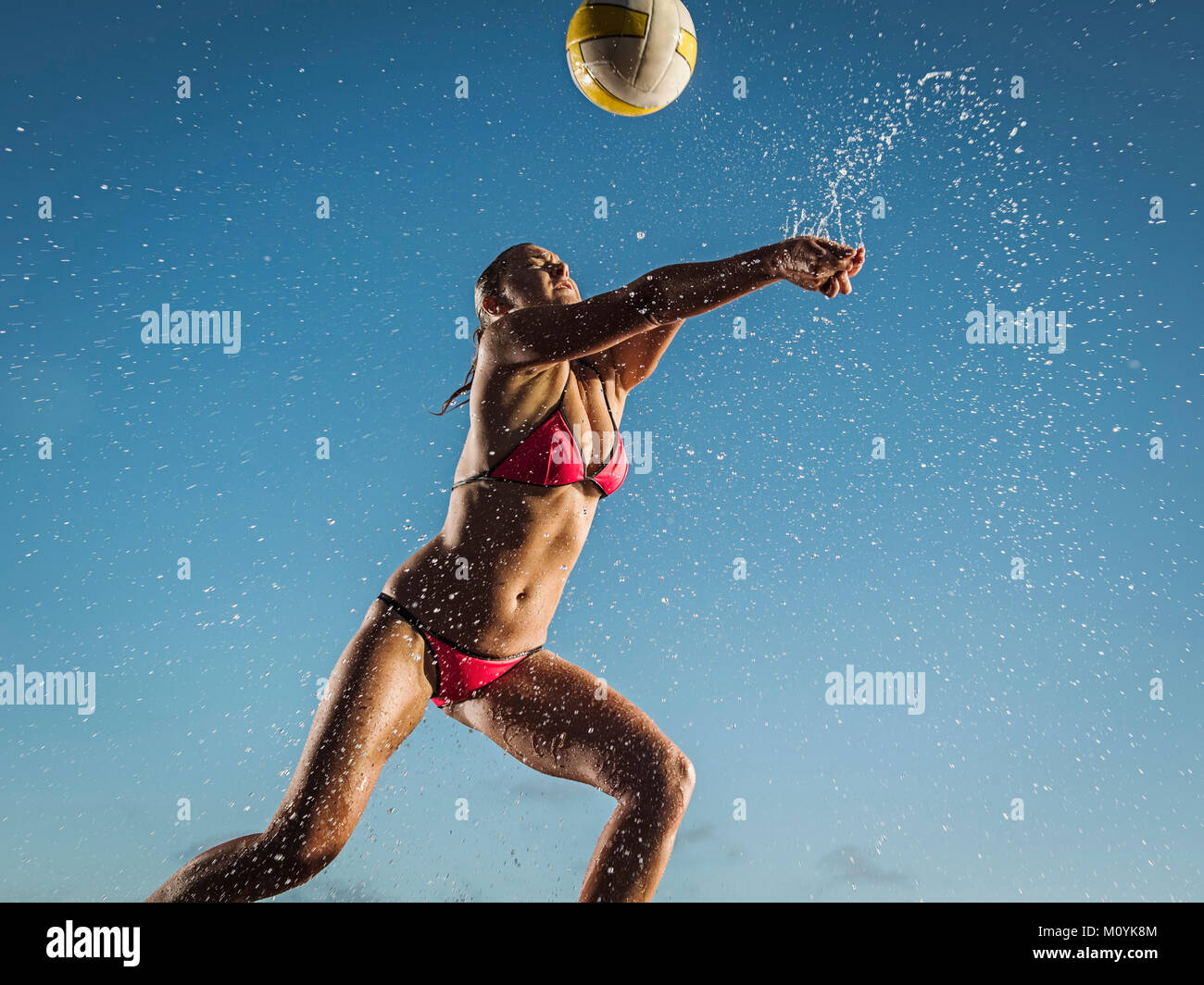 Water splashing on Caucasian woman playing volleyball Stock Photo