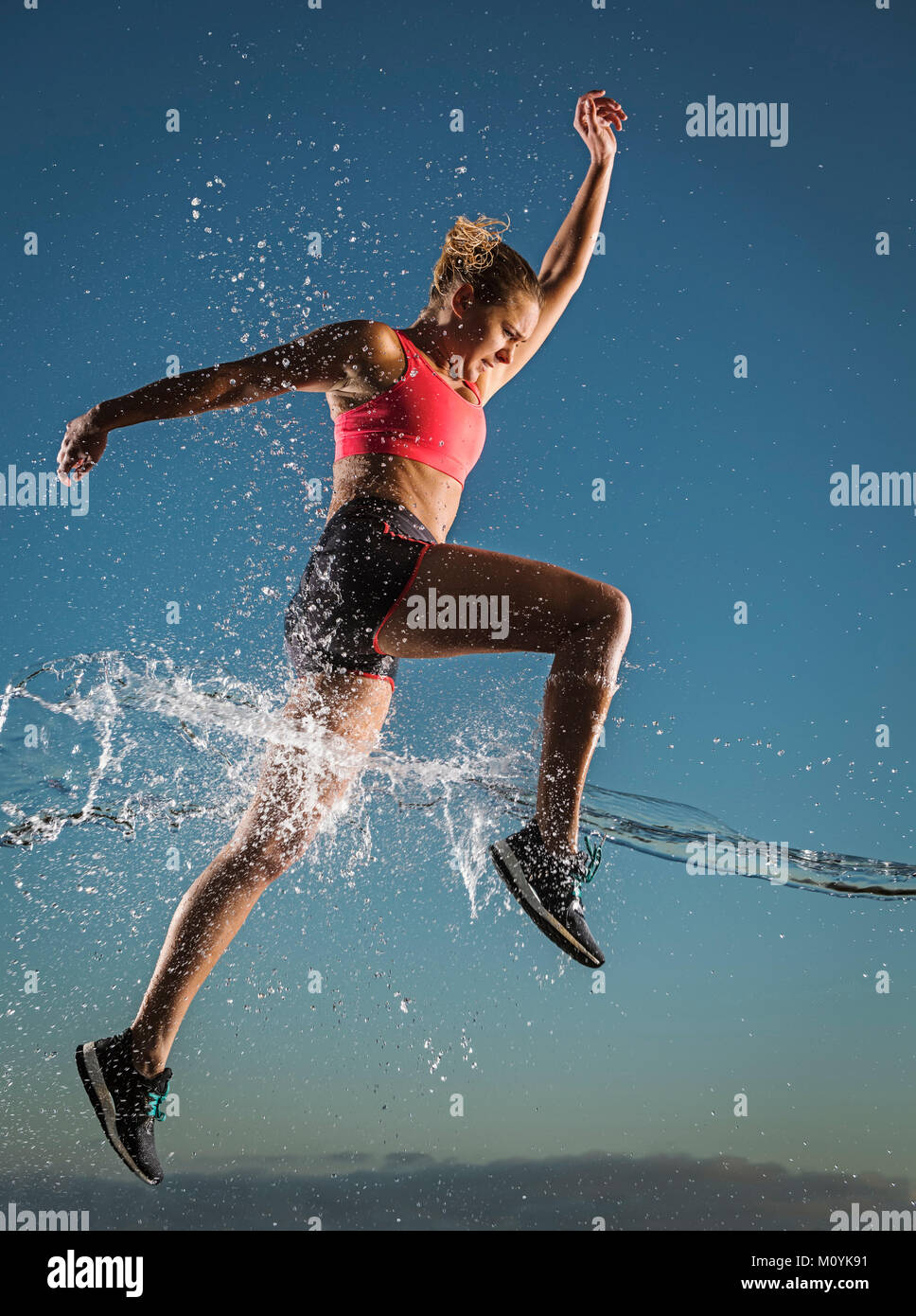 Water splashing on Caucasian woman running in sky Stock Photo