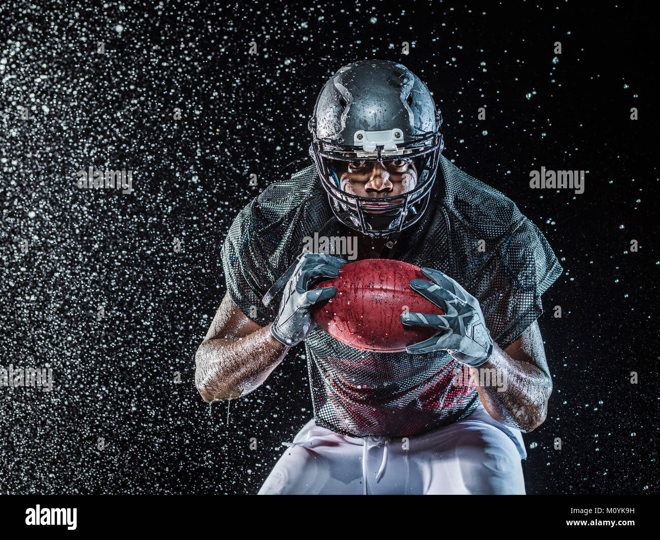 Water splashing on black football player Stock Photo - Alamy
