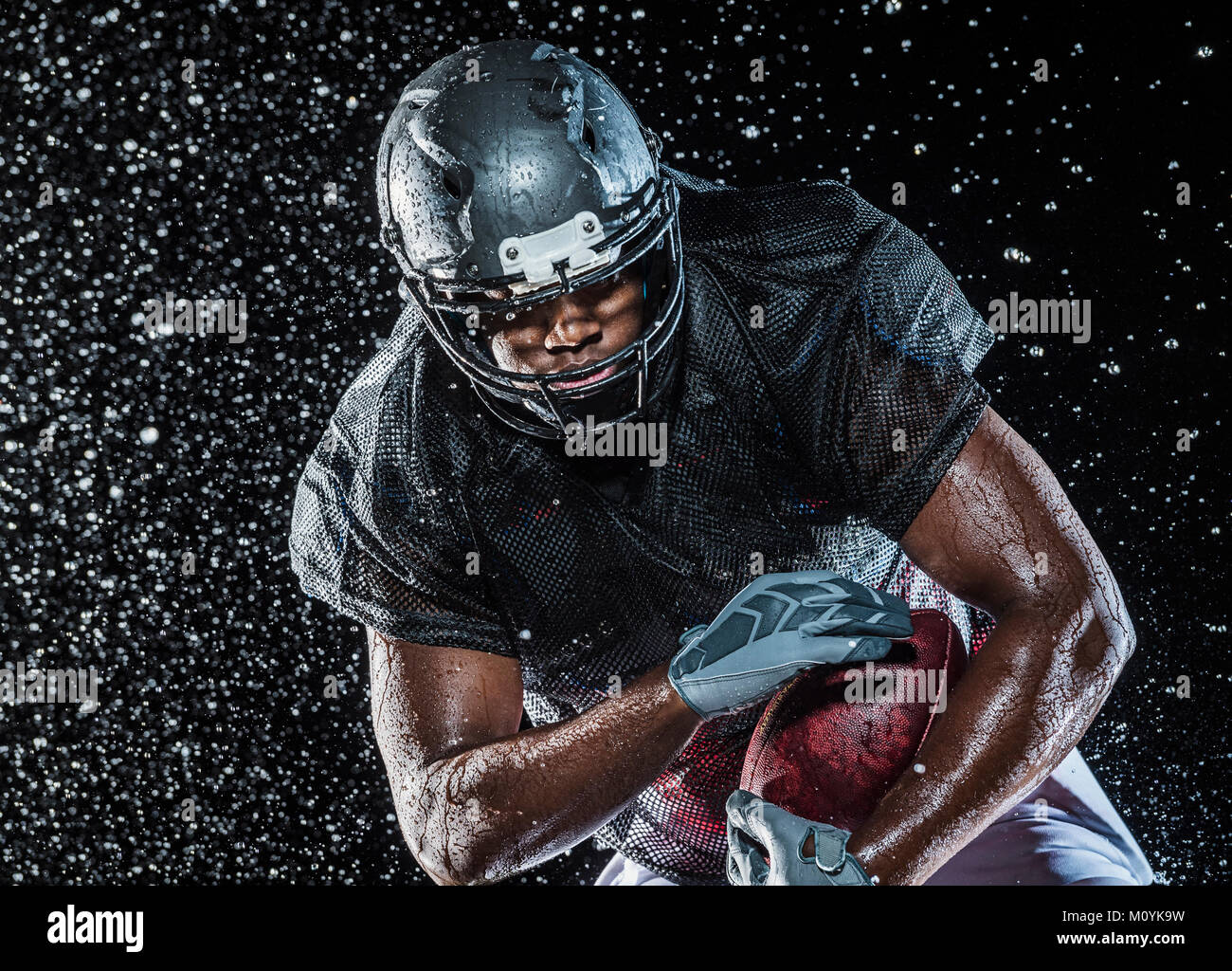 Water splashing on black football player Stock Photo